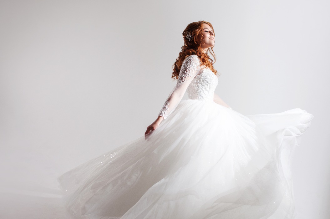Eine bezaubernde junge Braut in einem prächtigen Brautkleid. Heller Hintergrund.